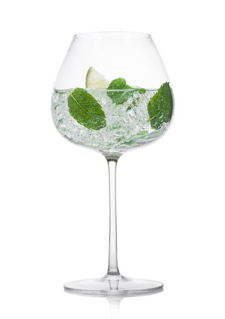 Glass of fresh sparkling water lemonade with mint and ice cubes and lime slice on white background. Refreshing summer soda drinkの写真素材