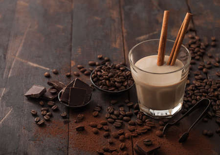 Crystal glass of Irish cream baileys liqueur with cinnamon, coffee beans and powder with dark...