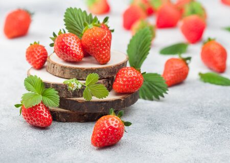 Fresh raw organic summer strawberries with a lot of vitamins and leaf on round timber boards on light table background.の写真素材