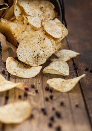 Potato crisps crunchy chips with  black pepper in steel snack bucket on wooden table background. Top viewの写真素材