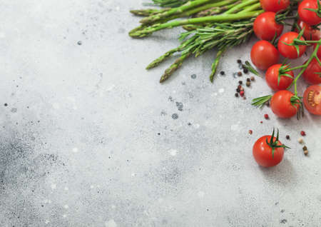 Light food background with asparagus, cherry tomatoes and rosemary on light background. Space for textの写真素材