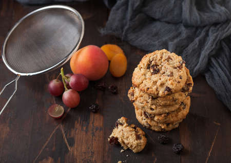 Homemade organic oatmeal cookies with raisins and apricots on dark wood background with apricot and grapes.の写真素材