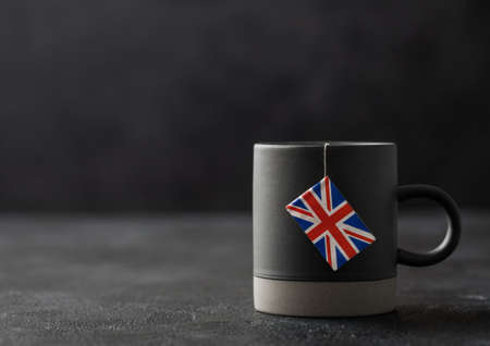 Teabag with flag of United Kingdom in grey ceramic cup on dark background. Afternoon tea traditionの写真素材
