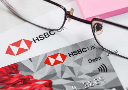 LONDON, UK - OCTOBER 14, 2020: HSBC UK bank debit card with glasses and blue pen on bank statement paperwork.のeditorial素材