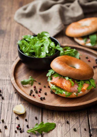 Fresh healthy organic sandwich with bagel and salmon, cream cheese and wild rocket in bowl plate on wooden table background with towel.の写真素材