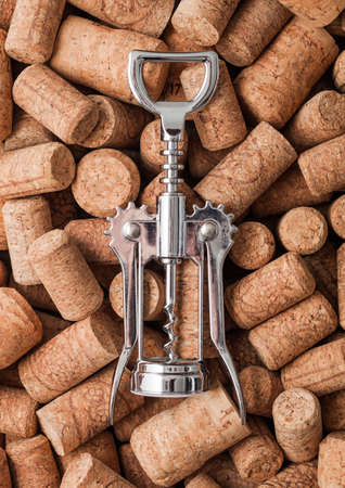 Steel modern corkscrew on top of various wine corks. Macro