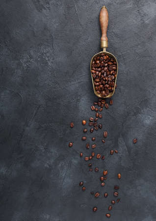 Fresh raw coffee beans in vintage steel scoop on black background.の写真素材