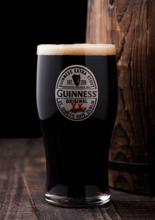 LONDON, UK - APRIL 27, 2018: Original glass of Guinness extra stout beer  next to old wooden barrel. Guinness beer has been produced since 1759 in Dublin, Ireland.のeditorial素材