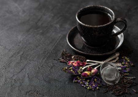 Tea cup with spoons and various tea on black. Black and green loose tea,rose buds,blue mallow flowersの写真素材