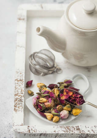 Rose buds mix tea on cup shape ceramic plate and tea ball strainer infuser and ceramic teapot in white wooden box. Macroの写真素材