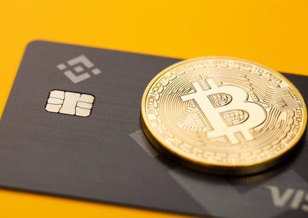 LONDON,UK - NOVEMBER 19, 2022: Binance visa credit card with bitcoin on yellow background. Most popular cryptocurrency platform. Macroのeditorial素材