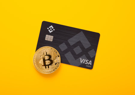 LONDON,UK - NOVEMBER 19, 2022: Binance visa credit card with bitcoin on yellow background. Cryptocurrency platform for trading and exchange. Top viewのeditorial素材