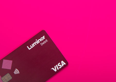 LONDON,UK - NOVEMBER 12, 2022: Luminor Visa debit contactless card on pink background.Top view.のeditorial素材
