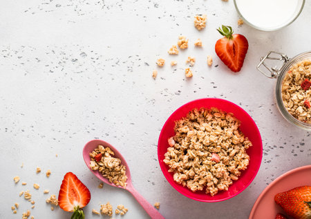 Granola with strawberry and milk in pink bowl plate on light background. Top view.の写真素材