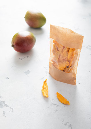 Pack of dried mango slices with two fresh raw mangoes. Top view.の写真素材