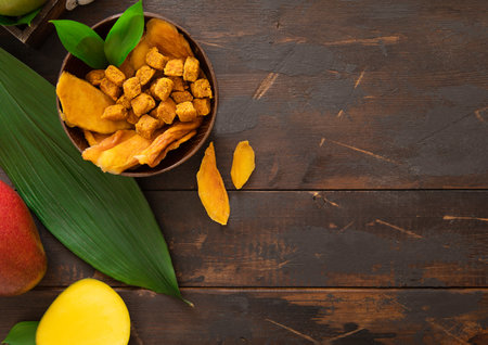 Mango dried slices and balls in bowl plate on wooden background.Top view.の写真素材