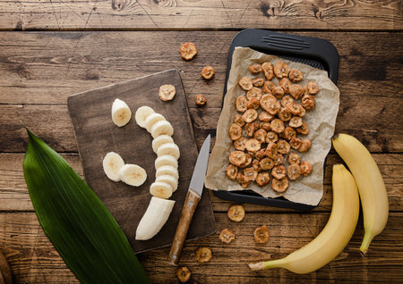 Fresh raw banana slices with dried banana chips on wooden background with green leaf.Top viewの写真素材