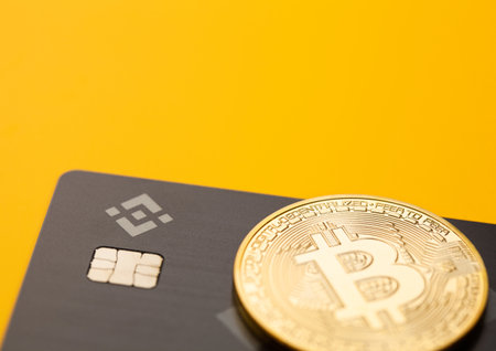 LONDON,UK - NOVEMBER 19, 2022: Binance visa credit card with bitcoin on yellow background. Most popular cryptocurrency platform. Close upのeditorial素材