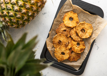 Organic sweet pineapple circle slices on in baking tray with ripe pineapple on light table.の写真素材