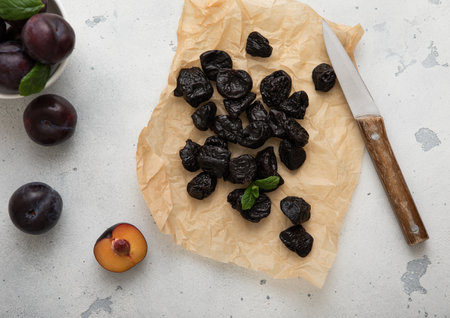 Dried sweet prunes with plums and kitchen knife on light bacground.の写真素材