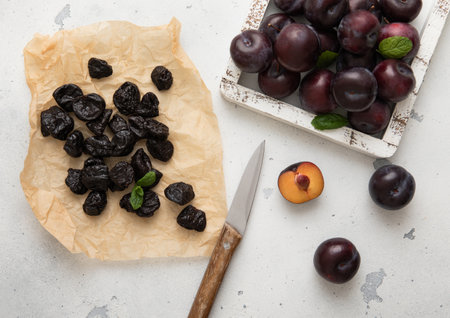 Dried sweet prunes with plums and kitchen knife on light bacground.の写真素材