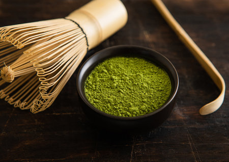 Green matcha tea with bamboo spoon and whisk on black background.の写真素材