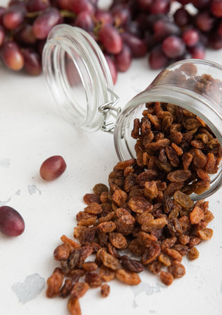 Brown dried sweet raisins in glass jar on light background.の写真素材