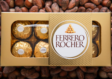 LONDON, UK - MARCH 10, 2024: Box of Ferrero Rocher chocolate candies on top of hazelnut and cocoa background.のeditorial素材