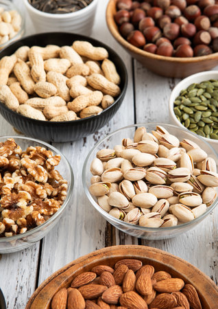 Mixed raw nuts and seeds in bowls on kitchen...