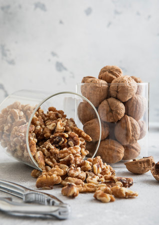 Glass jars with healthy raw walnut whole and peeled nuts on white kitchen table.の写真素材