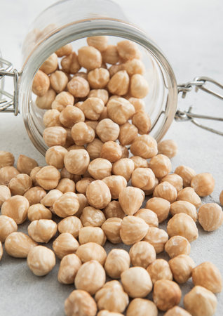 Raw peeled hazelnut nuts snack in glass jar on white kitchen table.の写真素材