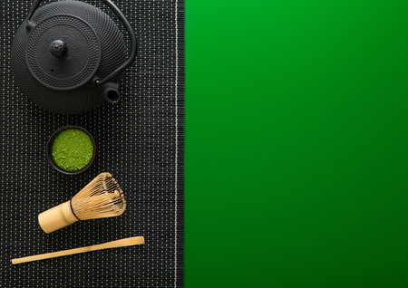 Organic matcha green tea powder with bamboo whisk and spoon and japanese traditional iron cast kettle on green background.の写真素材