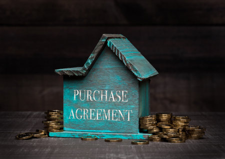 Wooden house model with coins next to it with conceptual text. Purchase Agreementの写真素材
