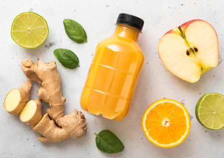 Ginger and orange energy shot immune drink with fresh raw ginger root on light background.の写真素材