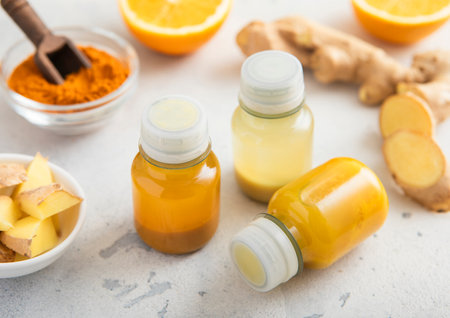 Immune ginger and turmeric energy shot drink with ginger root and turmeric powder on light background.の写真素材