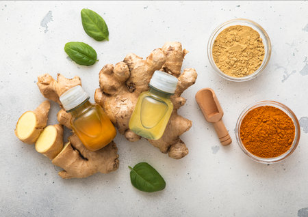Bottles of immune turmeric ginger energy shot drink with fresh raw ginger roots and oranges fruits on light background.の写真素材