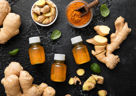 Bottles of immune turmeric spicy energy shot drink with ginger root and grounded turmeric powder on black background.の写真素材
