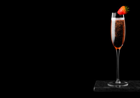 Elegant glass of pink rose champagne with strawberry on top on black marble board on black background.の写真素材