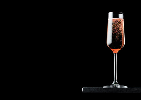 Elegant glass of pink rose champagne with bubbles on black marble board on black.の写真素材