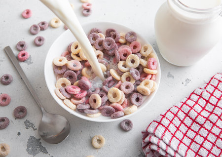 Various fruits breakfast cereal circles in plate and pouring milk into it with blueberry,banana and strawberry flavour.の写真素材