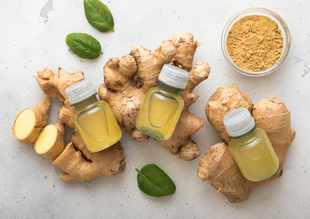 Bottles of immune ginger energy shot drink on top of fresh raw ginger root to light background.の写真素材