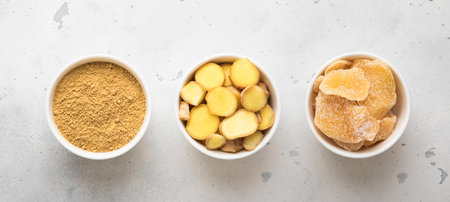 Ginger root slices and powder and ginger slices with sugar on light kitchen background.の写真素材
