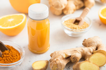 Immune orange and turmeric energy shot drink with ginger root and turmeric powder on light background.の写真素材