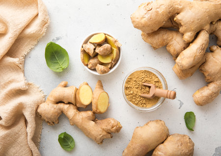 Fresh ginger root slices with melted ginger powder on light kitchen background.の写真素材
