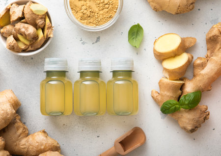Immune ginger energy shot drink bottles with fresh raw ginger root and powder on light background.の写真素材