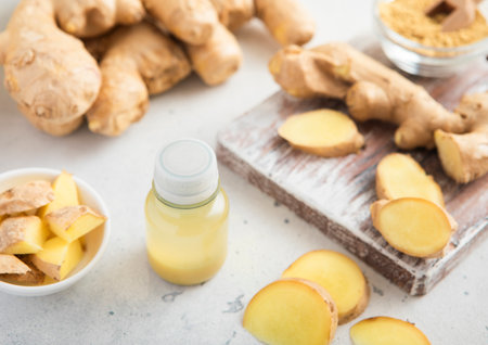 Immune ginger energy shot drink bottles with fresh raw ginger root on light background.の写真素材