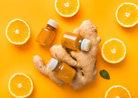 Bottles of turmeric and orange energy immune shot drink with fresh oranges slices on orange background.Top view.の写真素材