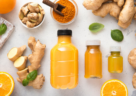 Ginger and orange energy shot immune drink with ginger root and turmeric powder on kitchen...
