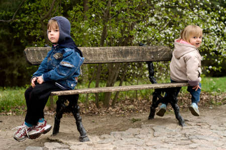 The offended boy and the girl sit on a bench in parkの写真素材