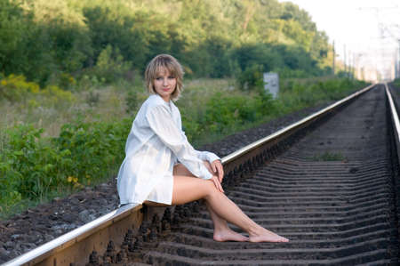 The beautiful young woman, sits on the railwayの写真素材